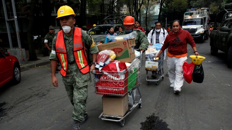 Soldiers carry donations of items for rescue workers and victims next to at a collapsed building. Photograph: Henry Romero/Reuters