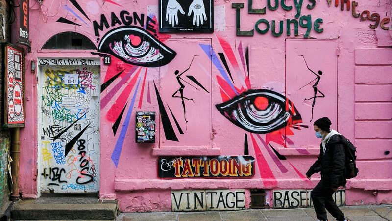 A member of the public wearing a face mask pass graffiti & murals in Temple Bar, Dublin on Thursday. Photograph: Gareth Chaney/Collins