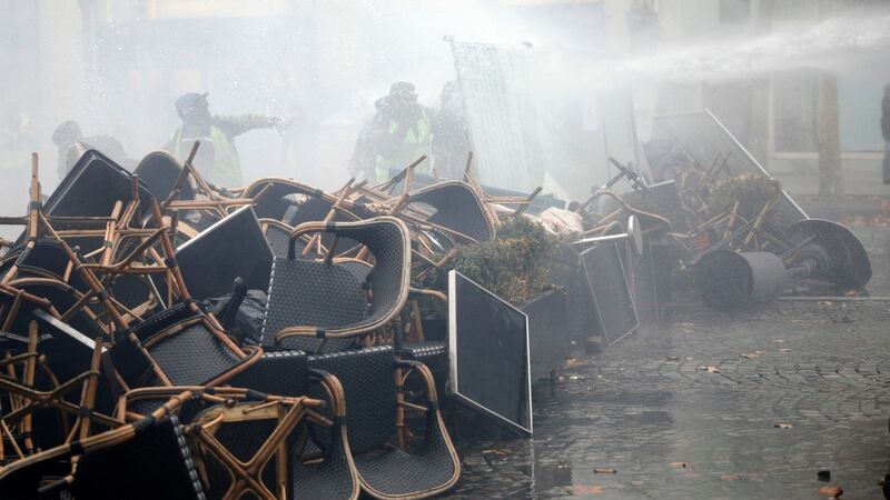 A police water cannon sprays water to disperse demonstrators standing behind a makeshift barricade of chairs and tables from cafes, during clashes on the Champs-Élysées avenue in Paris on Saturday. Photograph: Kamil Zihnioglu/AP