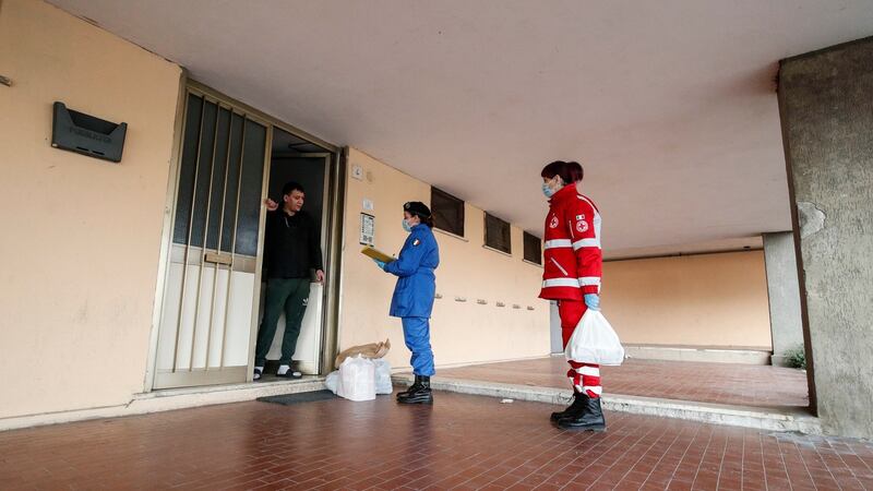Italian Red Cross medical staff and Italian Civil Protection members deliver food supplies to residents locked in their homes  in Civitavecchia, near Rome. Photograph: Giuseppe Lami/EPA