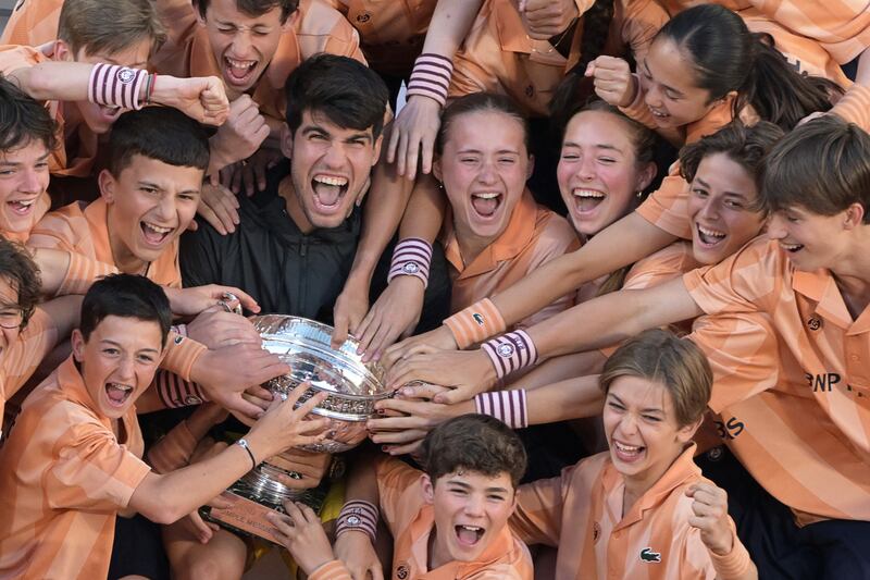 Carlos Alcaraz celebrates with the trophy and with ball boys and girls after winning his men's singles final match. Photograph: Bertrand Guay/AFP via Getty Images