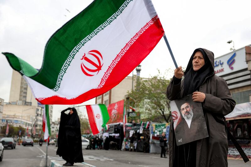 A woman holds a picture of Iran's new Supreme Leader Mojtaba Khamenei while waving a national flag along Enghelab (Revolution) Square in central Tehran. Photograph: Getty Images