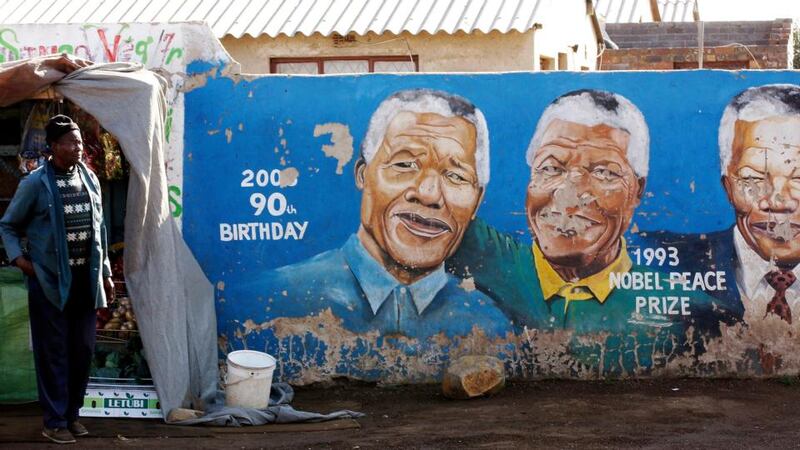 A man stands outside his makeshift shop near a wall mural of former South African president and anti-apartheid hero Nelson Mandela in Soweto yesterday. Photograph: Siphiwe Sibeko/Reuters