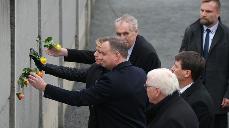 Czech President Milos Zeman, Slovak President Zuzana Caputova, Polish President Andrzej Duda, Hungarian President Janos Ader and German President Frank-Walter Steinmeier stick flowers into slats of a still-standing portion of the Berlin Wall following a ceremony to celebrate the 30th anniversary of its fall. Photograph: Sean Gallup/Getty