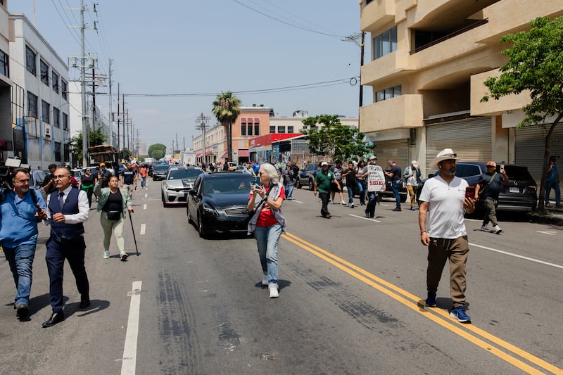 Protesters walk the street near the site of a federal immigration raid in Los Angeles on Friday. Federal agents in tactical gear armed with military-style rifles threw flash-bang grenades to disperse an angry crowd as they conducted an immigration raid on a clothing wholesaler. Photograph: Alex Welsh/The New York Times
                      