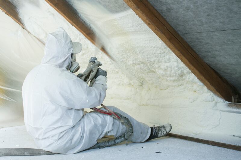 An attic retrofitting of insulation is carried out by a technician using spray polyurethane foam in a roof space. Photograph: iStock