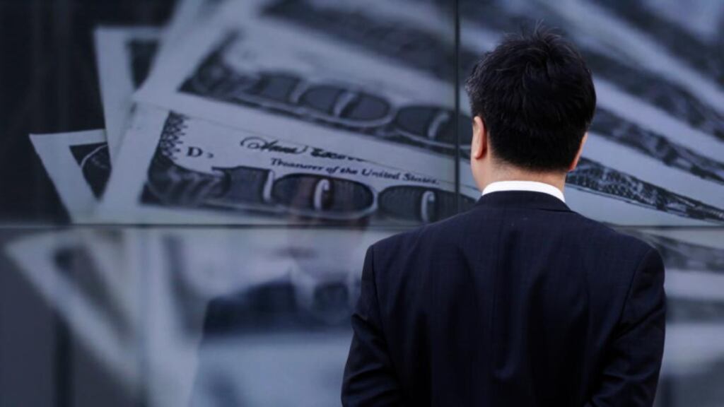 A businessman looks at a screen displaying a photo of US dollar bank notes in Tokyo today. The yen has hit fresh lows against a host of major currencies, resuming its slide after the Bank of Japan lost no time in launching its new easing policy to underline its determination to beat deflation. Photograph: Toru Hanai/Reuters