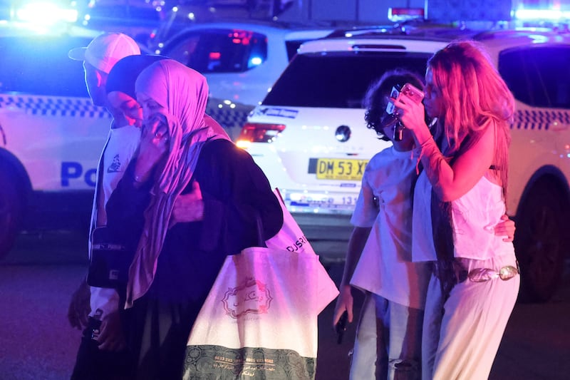 People cross a street next to police vehicles after a shooting incident at Bondi Beach in Sydney. Photograph: David Gray/AFP/Getty Images