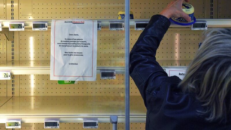 A sign reads “Due to a shortage of the raw material to make butter, we are not able to supply and sell you this product” as a woman takes a last pack of butter from an empty  supermarket fridge on October 25th in Reze, western France. Photograph:  Loic Venanceloic Venance/AFP/Getty Images