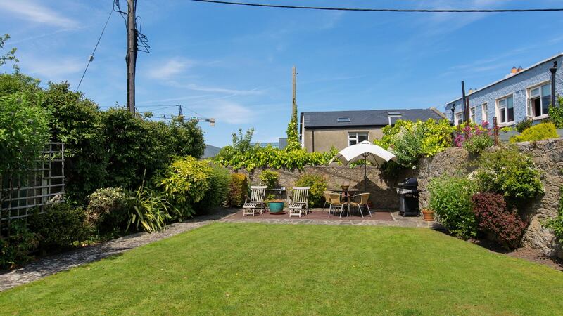 The rear garden at Avoca Lodge  is laid out as lawn bordered with shrubs and a patio to the rear
