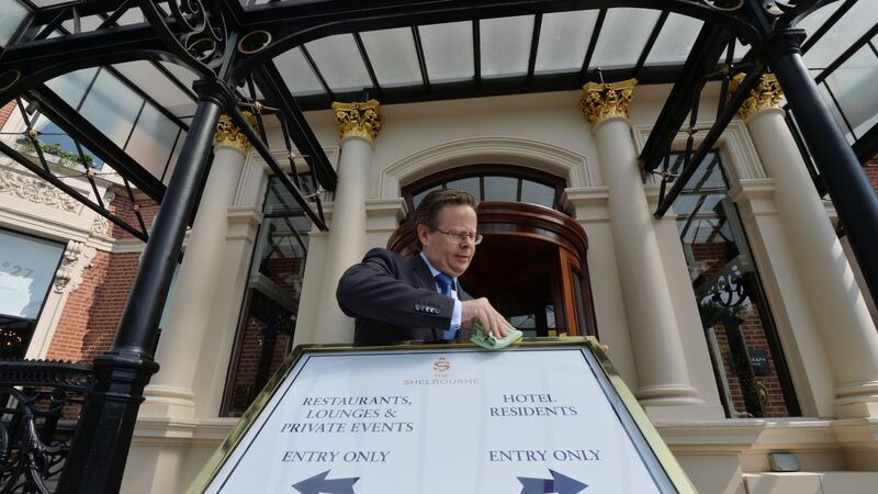 Shelbourne Hotel manager Lucius Farrell  adjusting Covid-19 signage outside the hotel. Photograph: Alan Betson