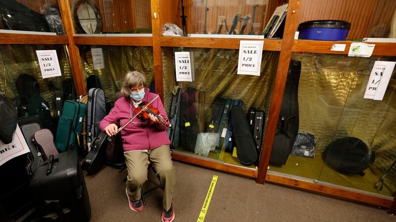 Maria Byrne  plays a violin while waiting for one of her last customers. Photograph: Alan Betson/The Irish Times