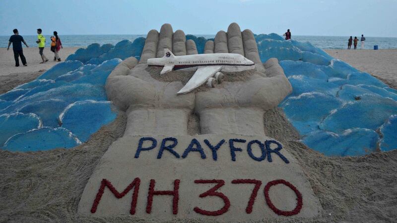Beachgoers walk past a sand sculpture made by Indian sand artist Sudersan Pattnaik with a message of prayers for the missing Malaysian Airlines flight MH370. Photograph: Asit Kumar/AFP/Getty Images