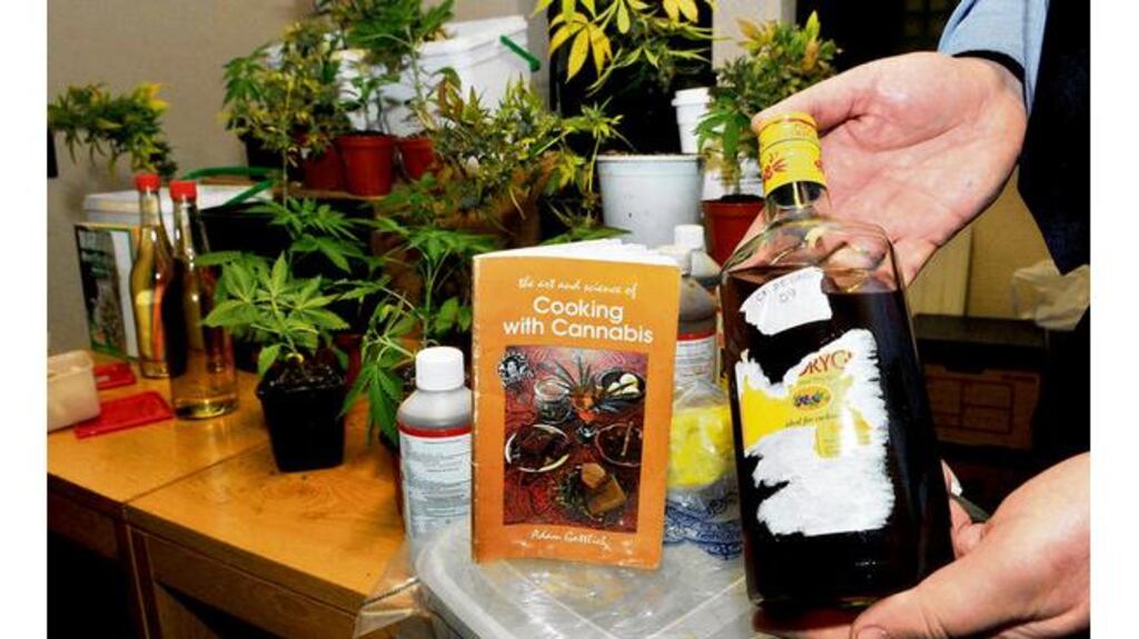A garda displays a bottle of "Creme de Grass" liquor (cannabis liquor) gathered during a raid on a house in Glantanewhich also uncovered equipment to grow cannabis, cannabis cookies, cannabis butter and cannabis plants. Photograph: Clare Keogh/Provision