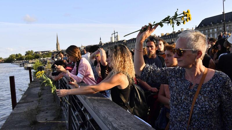 Activists  throw flowers into the Garonne river  in Bordeaux on Tuesday, in a tribute to Steve Maia Caniço, who died after falling into the river Loire in Nantes following a police raid on a music festival in June. Photograph: Mehdi Fedouach/AFP/Getty Images