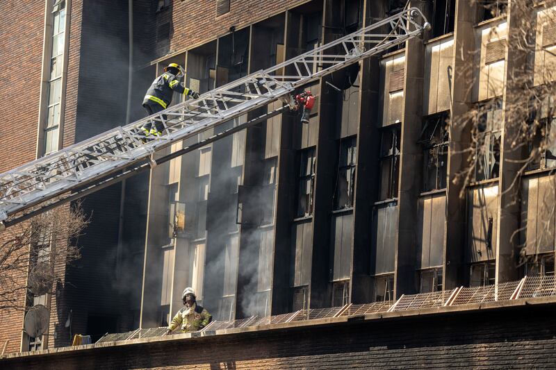 Firefighters at the scene of a fire in Johannesburg. The derelict building had been taken over by informal landlords. Photograph: Joao Silva/New York Times
                      