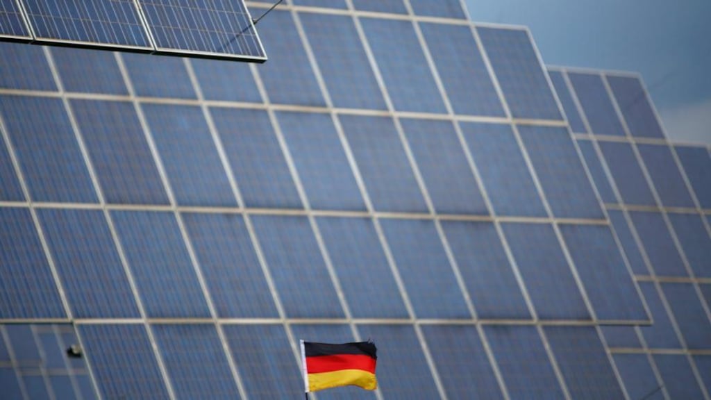 A German national flag  in front of solar panels in Bad Hersfeld. Photograph:  Lisi Niesner/Reuters