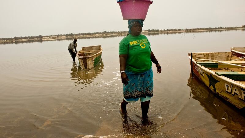 A Senegalese woman  carry a heavy load of  salt on to the shore at Lac Rose. Photograph: Lar Boland