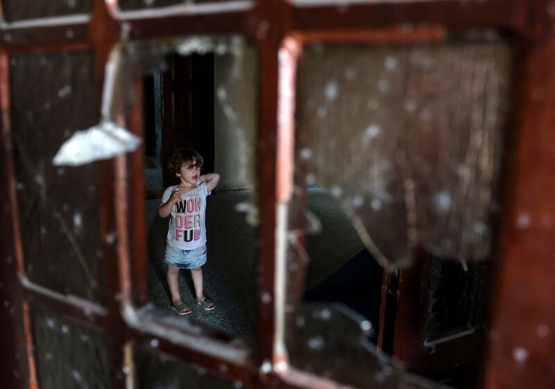 A Palestinian child stands behind a shattered window inside a building damaged following Israeli air strikes in Rafah on Sunday. Photograph: Said Khatib/AFP/Getty 