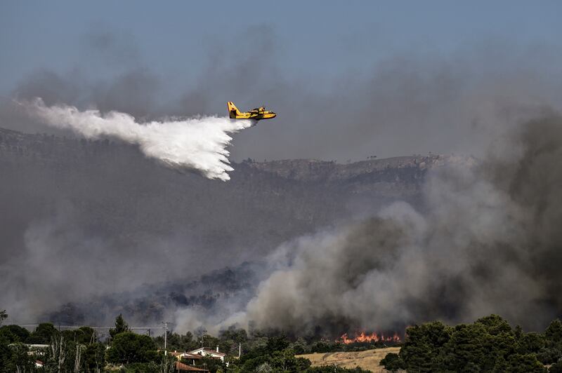 A firefighting plane sprays water during a fire in Dervenochoria, northwest of Athens. Photograph: SPYROS BAKALIS/AFP via Getty Images