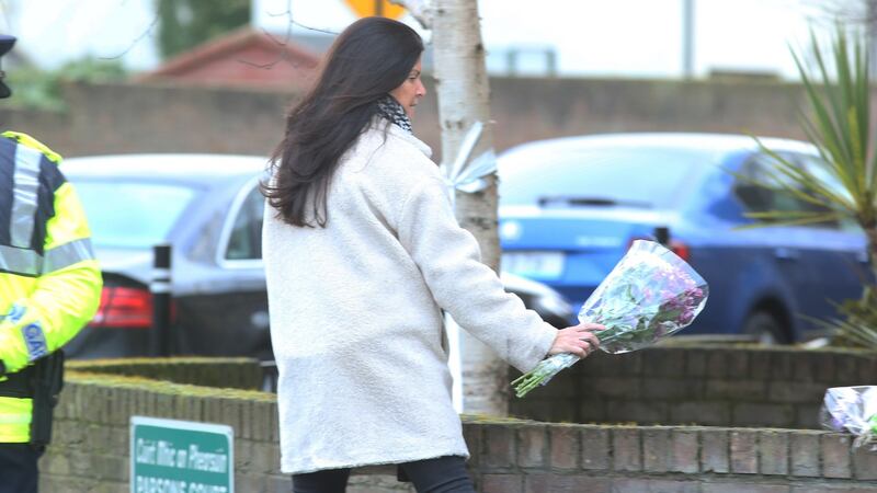 A woman leaves flowers  outside the house in Parson’s Court in Newcastle in which the bodies of three children were found.  Photograph:  Collins