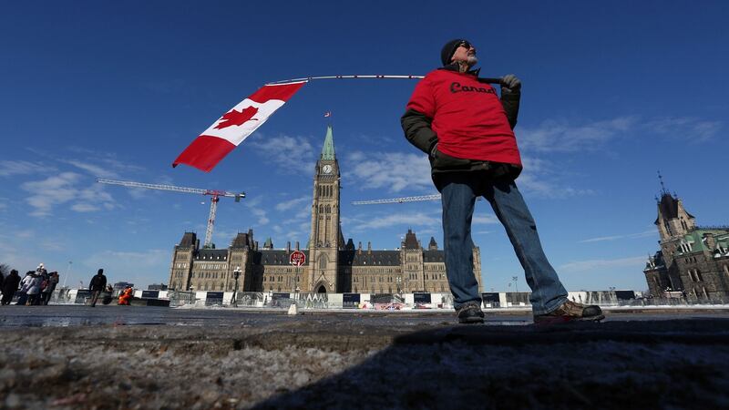 A man holds a Canadian flag near Parliament Hill in Ottawa as protests against vaccine mandates and coronavirus restrictions continue. Photograph:  Dave Chan/AFP via Getty Images