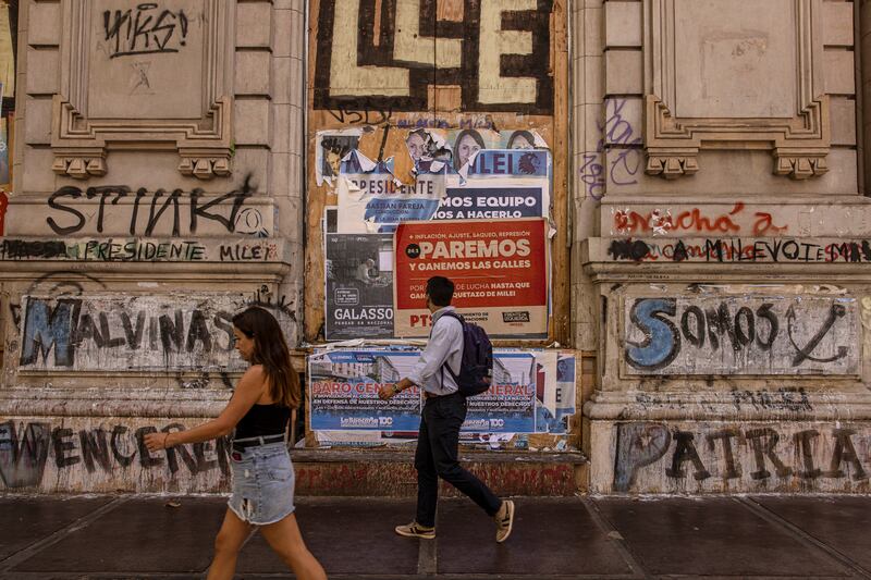 Pedestrians pass in front of old signs for Javier Milei’s successful presidential campaign, and other signs calling for a general strike, in Buenos Aires, Argentina on January 22nd. Photograph: Sarah Pabst/ New York Times