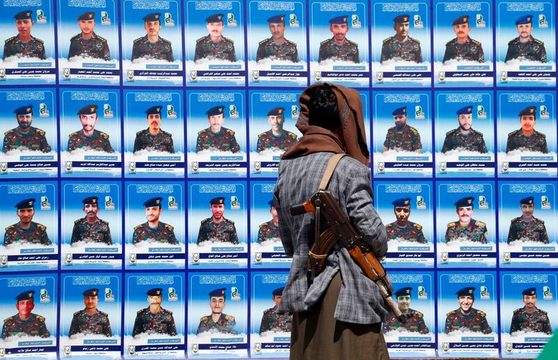 An armed Houthi fighter looks at a banner in Sanaa depicting portraits of colleagues who have died. Photograph: Yahya Arhab/EPA