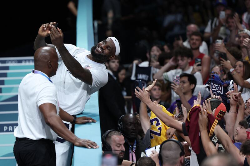 LeBron James takes selfie photos with a spectator's smartphone at the end of the men's preliminary round group C basketball match between Puerto Rico and USA during the Paris 2024 Olympic Games. Photograph:  Thomas Coex/AFP via Getty Images