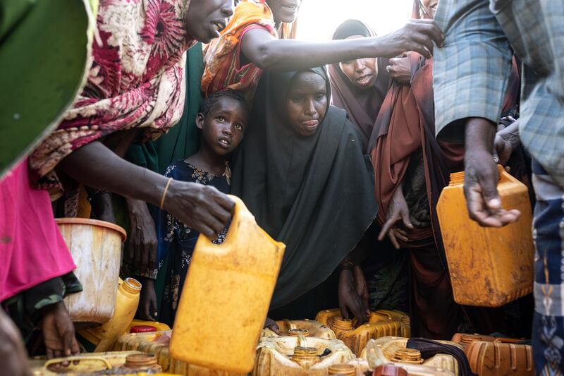 A donkey cart brings water to a camp housing people who fled the drought in Baidoa, in southern Somalia, on Nov. 4, 2022. Residents grab containers and run for the cart as soon as it appears.  (Andrea Bruce/The New York Times)