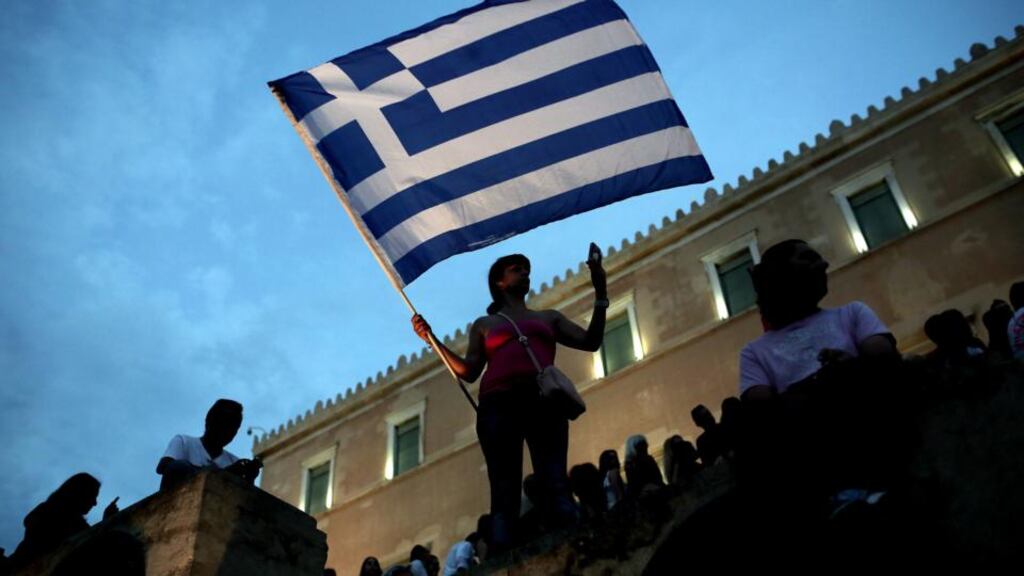 An anti-austerity protester holds a Greek flag in front of parliament. Photograph: Angelos Tzortzinis/AFP/Getty Images