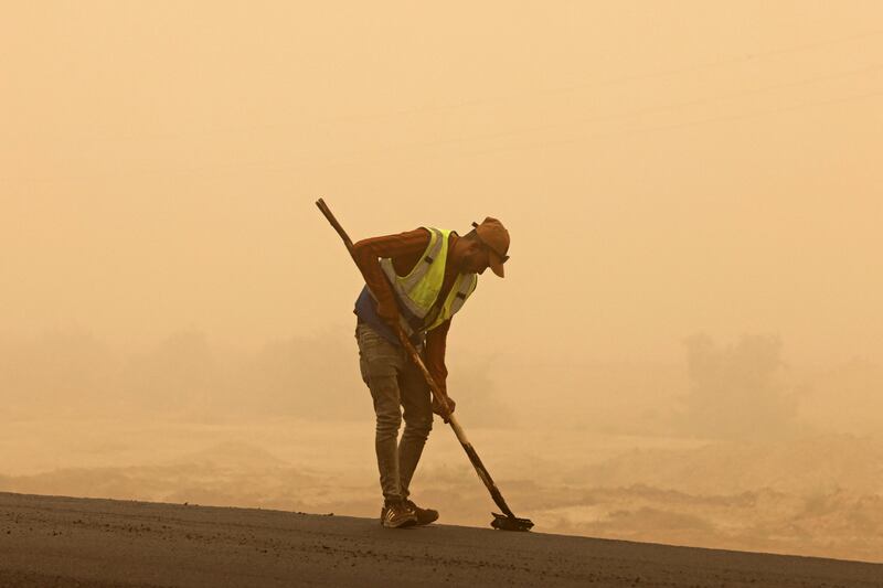 A worker sweeps a road during a sandstorm in Iraq's Diyala province. Photograph: Ahmad Al-Rubaye/AFP/Getty 