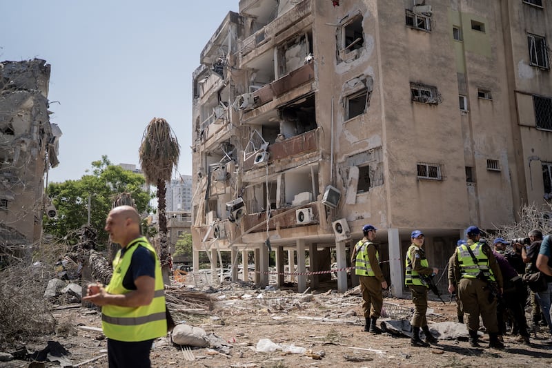 Israeli rescue team members survey damaged buildings in Holon. Photograph: Getty Images