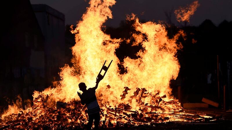 A child throws bits of wood onto a bonfire during the Twelfth of July celebrations. Photograph: Reuters