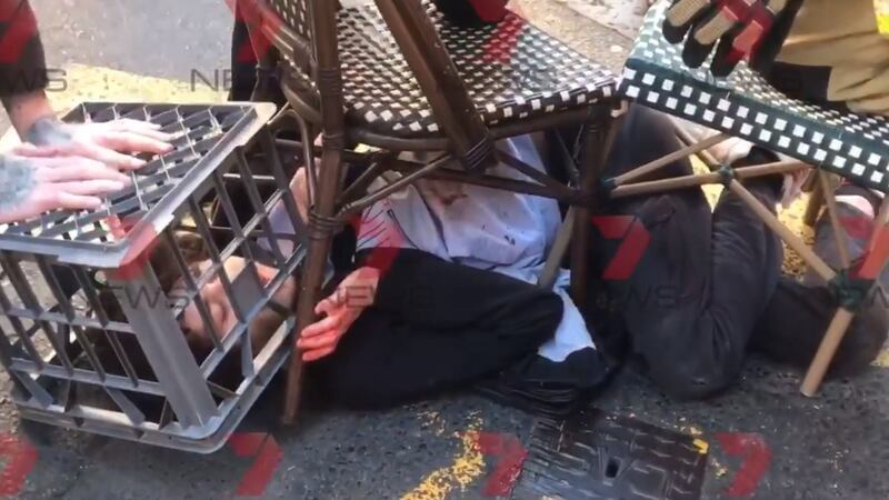 A man being restrained with the help of a milk crate and chairs  by members of the public in Sydney. Photograph:  Andrew Denney/7 News/PA Wire