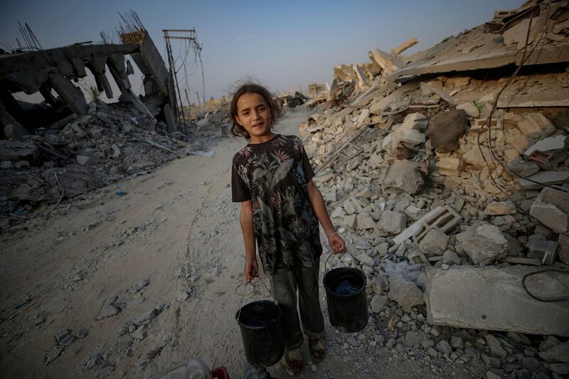 An 11-year-old girl with pails of water at the site of her family's destroyed home in Jabaliya, northern Gaza Strip, November 4th. Photograph: Mohammed Saber/ EPA
