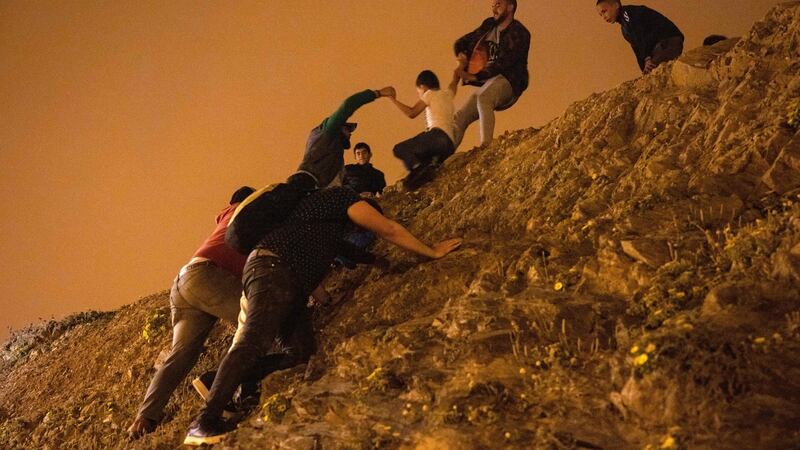 Moroccan migrants climb a rocky cliffside  as they attempt to cross the border from Morocco to Spain’s north African enclave of Ceuta. Photograph: Fadel Senna/AFP via Getty Images)