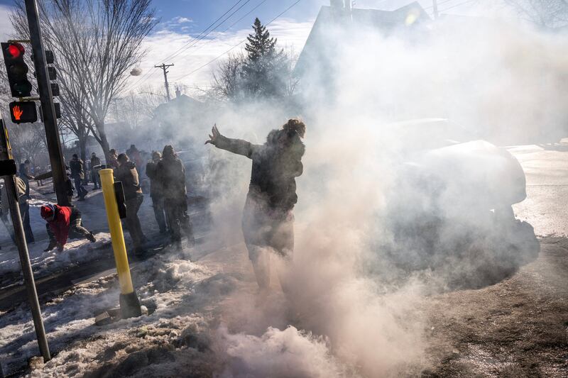 A woman throws a snowball at federal agents who had tossed tear gas canisters into a crowd during an immigration enforcement operation in Minneapolis. Photograph: David Guttenfelder/The New York Times
                      
