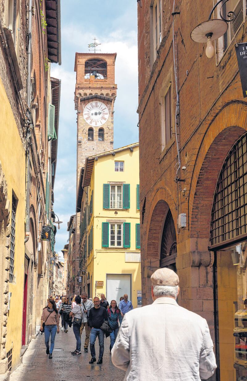 The 50 meters high Torre delle Ore seen down Via Fillungo. Lucca, Lucca Province, Tuscany, Italy. The origins of the tower go back to the Middle Ages. It is the tallest tower in Lucca. The current clock works with a mechanism dating from 1754. (Photo by: Ken Welsh/UCG/Universal Images Group via Getty Images)