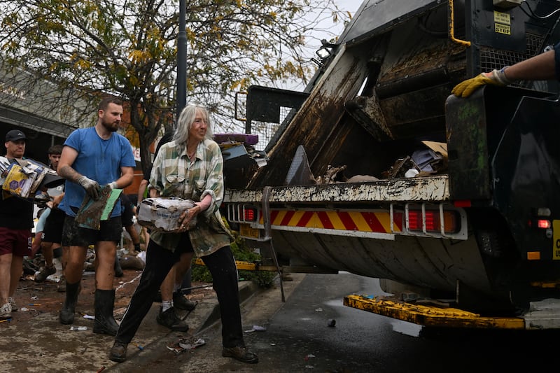 Australia floods Volunteers help out locals to clear flood-damaged goods from shops. Photograph: Saeed Khan/AFP/Getty Images        
