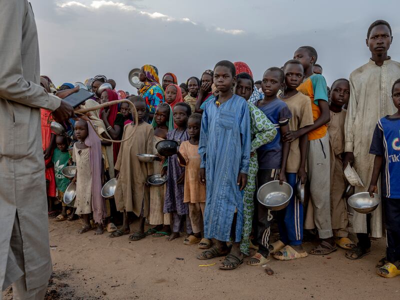 A man with a whip tries to control a crowd of Sudanese refugees who were waiting to receive food at an impromptu aid distribution on the outskirts of a refugee camp in Adre, Chad. Photograph: Ivor Prickett/New York Times
                      