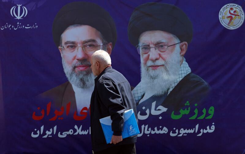 A man walks past a banner with pictures of Iran's slain supreme leader Ayatollah Ali Khamenei (right) and his son and successor Mojtaba Khamenei on a street in Tehran on Wednesday. Photograph: AFP via Getty