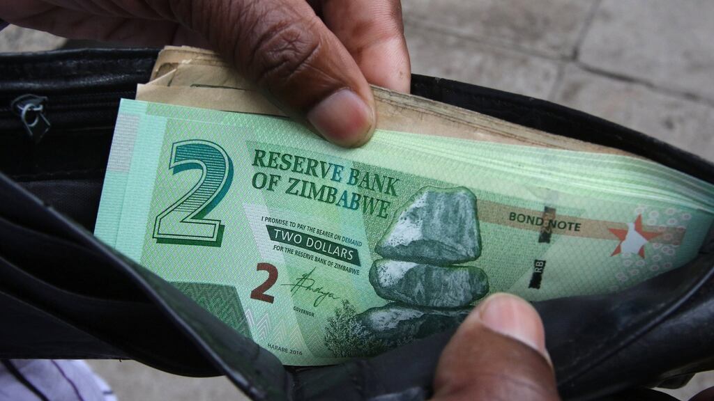 A Zimbabwean man shows off a new bond note outside a bank in Harare, Zimbabwe. Photograph: Philimon Bulawayo/Reuters