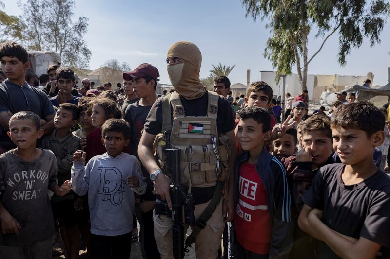 A Hamas fighter stands guard as hostages are handed over to the Red Cross in Gaza. Photograph: Saher Alghorra/The New York Times
                      