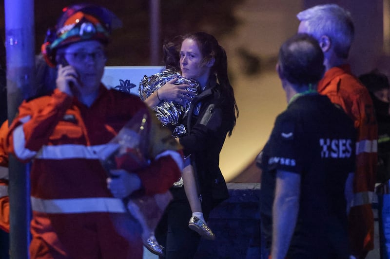 A woman holds a child in a blanket after a shooting incident at Bondi Beach. Photograph: David Gray/AFP/Getty Images