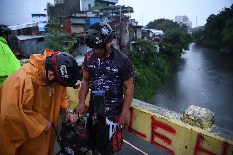 Village officers operate a siren to warn residents near a creek in Quezon city as Super Typhoon Noru slammed into the Philippines. Photograph: Ted Aljibe/Getty Images