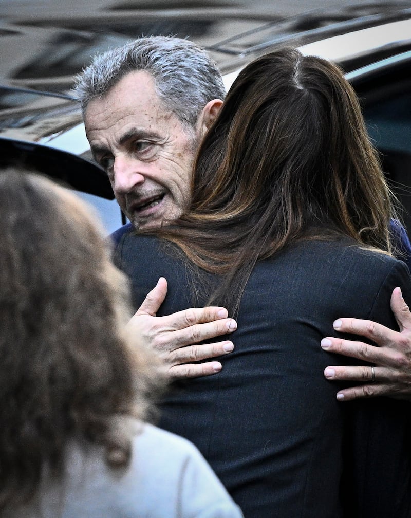 Nicolas Sarkozy hugs his wife Carla Bruni-Sarkozy as he leaves his home to present himself to prison authorities. Photograph: Julien de Rosa/AFP/Getty Images