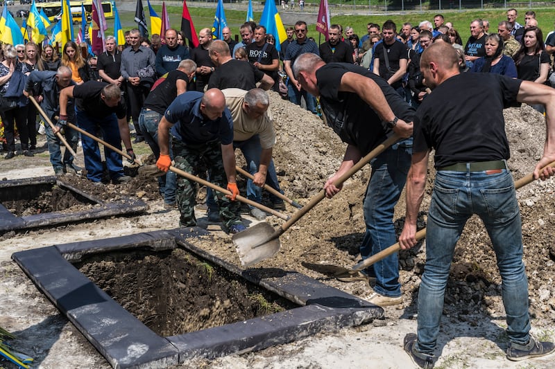 Grave diggers bury two Ukrainian soldiers after their funeral at Lychakiv Cemetery in Lviv, Ukraine, Photograph: Brendan Hoffman/The New York Times