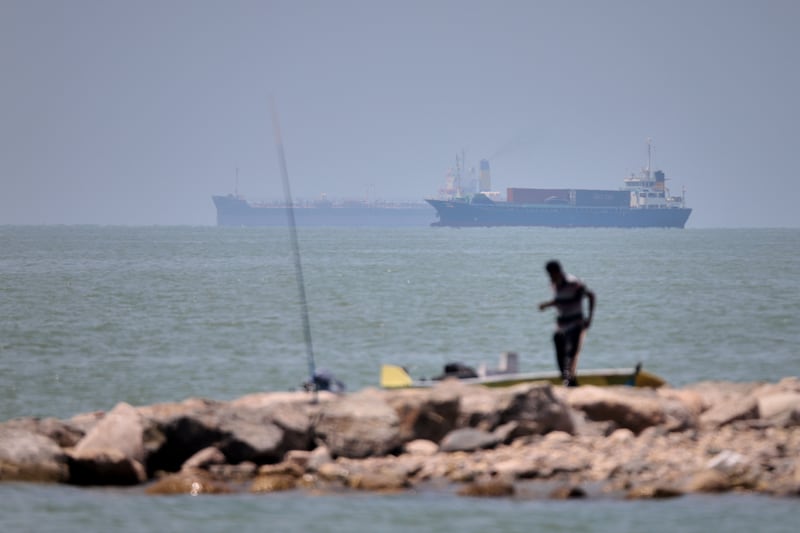 A man stands beside a fishing pole along the shore as cargo ships and commercial vessels are seen in the Strait of Hormuz off Bandar Abbas, Iran, on Thursday. Photograph: Amirhosein Khorgooi/ISNA/AP
