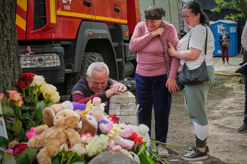 Mourners gather at a makeshift memorial beneath a tree near the destroyed building. Photograph: Efrem Lukatsky/AP
